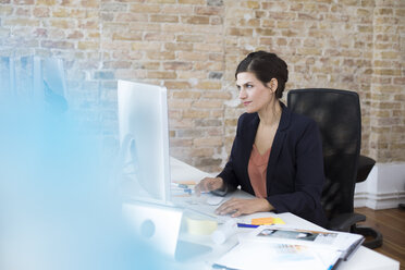 Geschäftsfrau arbeitet am Schreibtisch im Büro - FKF02495