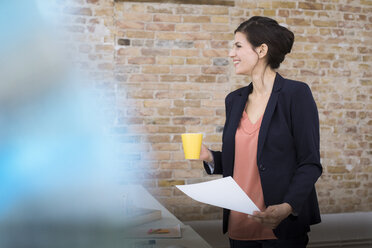 Smiling businesswoman standing in office - FKF02498