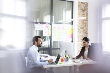 Businessman and businesswoman working at desk in office - FKF02512