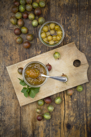 Jar of gooseberry jam, gooseberries and glass of preseved gooseberries on wood stock photo