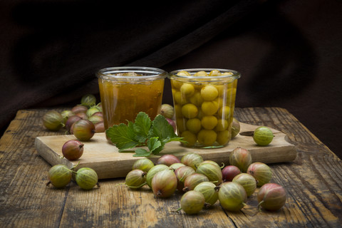 Jar of gooseberry jam, gooseberries and glass of preserved gooseberries on wood stock photo