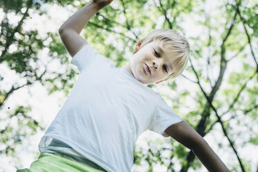 Porträt eines lächelnden kleinen Jungen, der auf einen Baum klettert - MJF02135