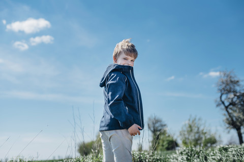 Smiling boy standing against blue sky stock photo