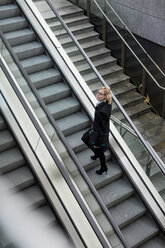 Businesswoman on escalator - MAUF01197