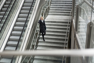 Businesswoman on stairs with cell phone - MAUF01198