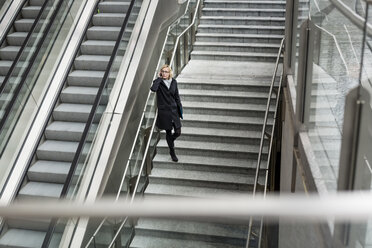 Geschäftsfrau auf der Treppe mit Mobiltelefon - MAUF01198