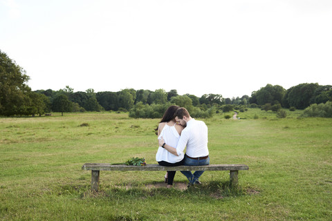 Rückansicht eines Paares auf einer Bank in einem Park, lizenzfreies Stockfoto