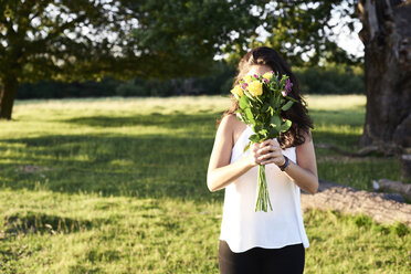 Junge Frau versteckt sich hinter einem Blumenstrauß - IGGF00053