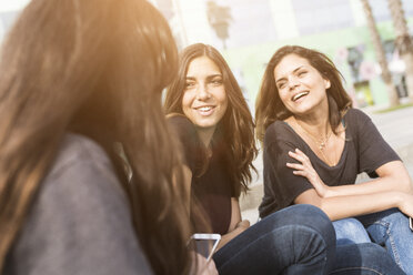 Three happy young women sitting outdoors - GIOF02984