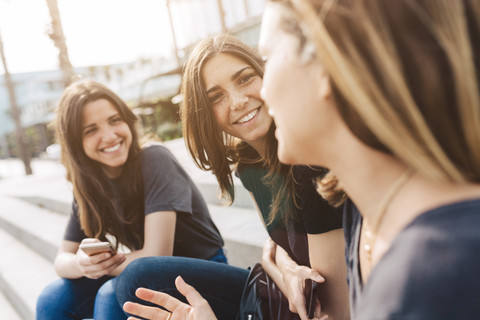 Three happy young women sitting outdoors stock photo