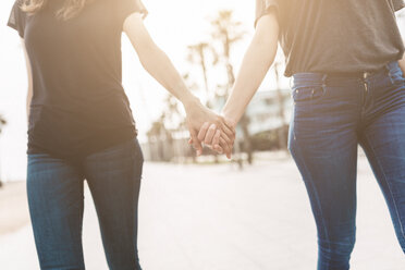 Zwei junge Frauen gehen Hand in Hand über die Promenade - GIOF02998