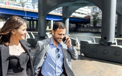 Smiling businessman on the phone and businesswoman in the city - MGOF03469