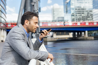 Businessman sending voice messages with his smartphone in the city - MGOF03472