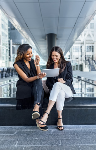 Zwei Geschäftsfrauen bei der Arbeit mit einem Tablet in der Stadt, lizenzfreies Stockfoto