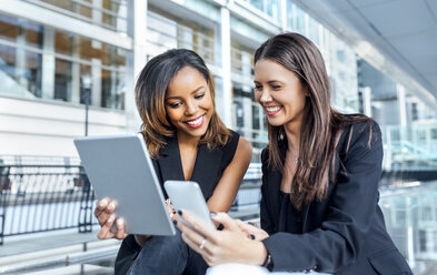 Two businesswomen working with smartphone and tablet in the city - MGOF03482