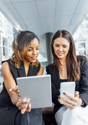 Zwei Geschäftsfrauen arbeiten mit Smartphone und Tablet in der Stadt - MGOF03483
