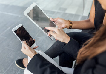 Close-up of two women using smartphone and tablet in the city - MGOF03484