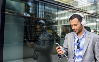 Businessman listening to music with headphones in the city - MGOF03513