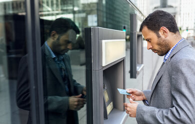 Businessman taking money at an ATM in the city - MGOF03519