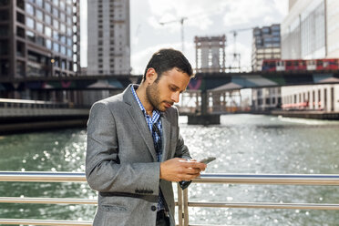 Businessman sending messages with his smartphone in the city - MGOF03523