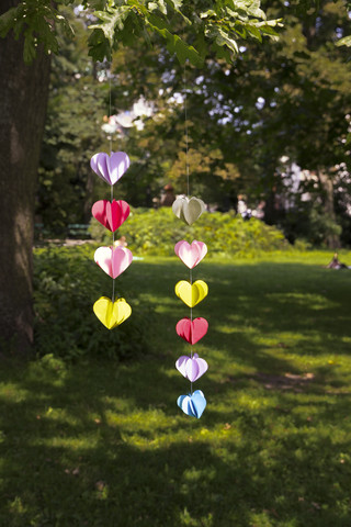 Herzförmige Girlande aus Papier hängt im Garten, lizenzfreies Stockfoto