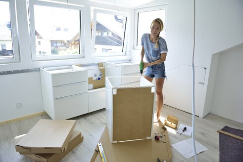 Woman assembling cabinet at home - ECPF00012