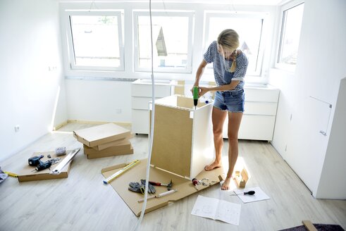 Woman assembling cabinet at home - ECPF00013