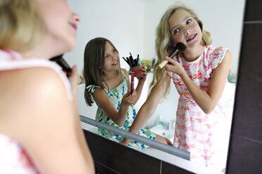 Two girls applying make up in bathroom - ECPF00025