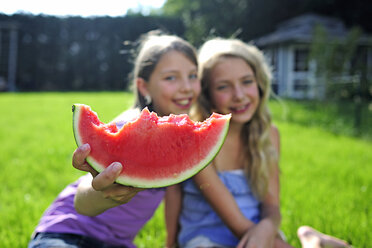Zwei glückliche Mädchen essen eine Wassermelone im Garten - ECPF00030