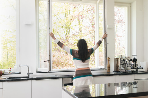 Frau in der Küche öffnet das Fenster, lizenzfreies Stockfoto