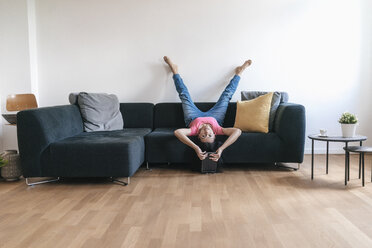Woman at home with tablet lying on sofa upside down - JOSF01244