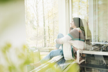 Woman in kitchen looking out of window - JOSF01245