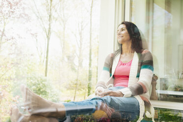 Confident woman at home looking out of window - JOSF01252