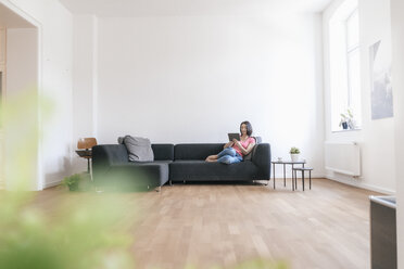 Woman at home using tablet on sofa - JOSF01258