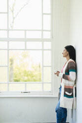 Woman at home looking out of window - JOSF01265