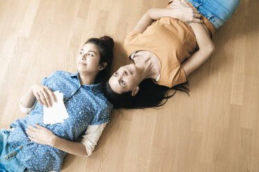 Zwei Frauen liegen auf dem Boden und halten Fotos - JOSF01275