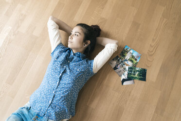Woman lying on the floor next to photos - JOSF01276