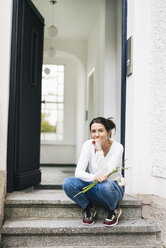 Frau mit Blumen auf der Türschwelle sitzend - JOSF01310