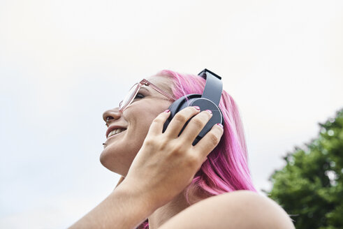 Young woman with pink hair listening to music outdoors - IGGF00075