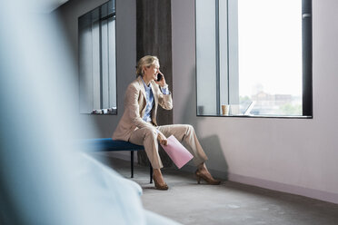 Lächelnde Geschäftsfrau am Telefon, die am Fenster sitzt - UUF11395