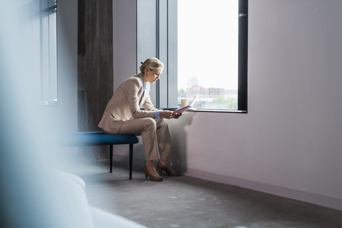 Geschäftsfrau sitzt am Fenster und liest ein Dokument, lizenzfreies Stockfoto