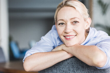 Portrait of smiling businesswoman leaning on chair - UUF11408