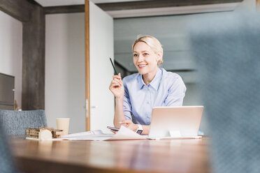 Smiling businesswoman working at desk in office - UUF11412