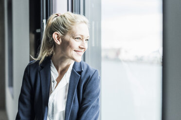 Smiling businesswoman looking out of window - UUF11418