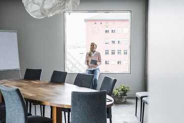 Lächelnde Geschäftsfrau im Konferenzraum am Fenster - UUF11440