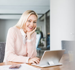 Portrait of smiling businesswoman using tablet in office - UUF11442