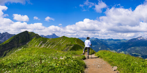 Deutschland, Allgäuer Alpen, Wanderer steht auf dem Weg und schaut auf die Panoramastraße vom Fellhorn zum Sollereck - WGF01103