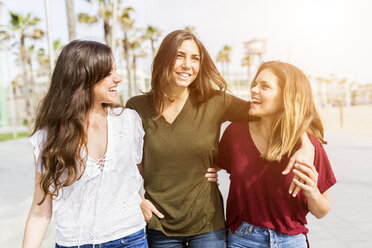 Three happy female friends strolling on the boardwalk - GIOF03002