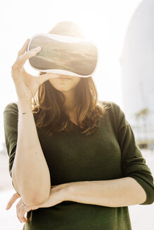 Junge Frau trägt VR-Brille im Freien - GIOF03010