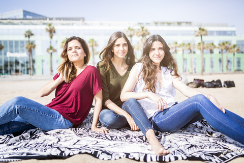 Three female friends relaxing on the beach stock photo